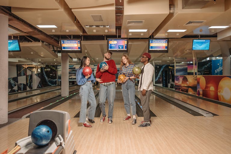 A group of young friends having fun bowling in an indoor alley, enjoying leisure time together.